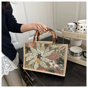 Detail of floral sequin embroidery on jute tote bag with bamboo-style handle