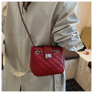 Detailed view of a red quilted leather shoulder bag with a silver chain and turn-lock clasp