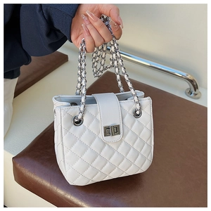Detail of white quilted leather bag with silver twist-lock and woven chain strap