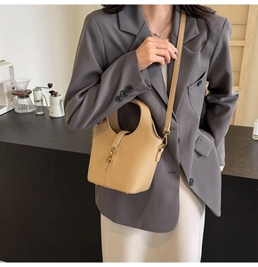 Détail du sac seau beige motif lychee avec breloque clé dorée et bandoulière réglable