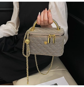Close-up of quilted chain bag featuring camellia detail and gold handle accessory