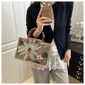Detail of woven handbag with sequin floral patterns and vintage bamboo U-shaped handle