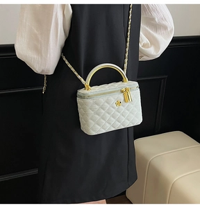 Detail of white quilted crossbody bag with golden flower emblem and chain strap on a model