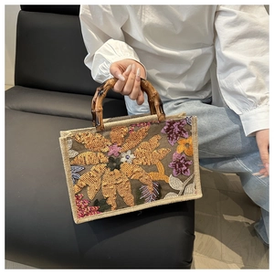 Close-up of sequin floral embroidery and vintage bamboo handle on a woven handbag