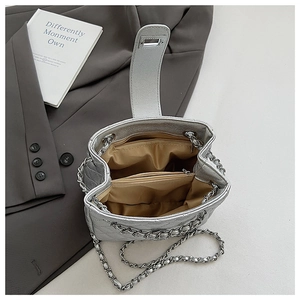 Detail view of silver quilted chain bag with dual compartments and sateen lining interior