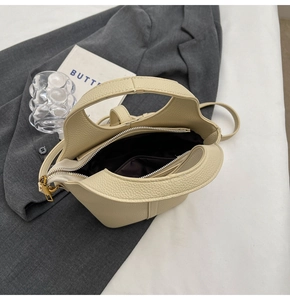 Vue de dessus du sac seau beige montrant l'intérieur, le zip et la bandoulière réglable
