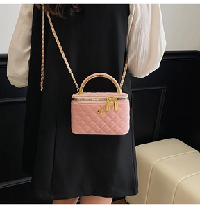 Detail of pink quilted crossbody bag with golden camellia logo and chain strap on model
