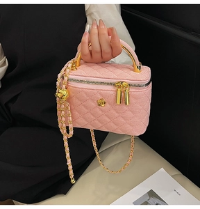 Close-up of pink quilted chain bag with golden camellia ornament and metal handle