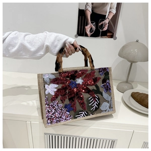Detail of floral sequin embroidery and natural bamboo handle on a retro tote bag