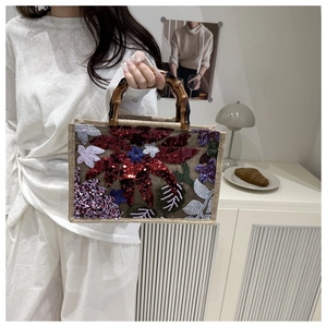 Detail of floral embroidery and sequins on a bohemian jute bag with bamboo handles