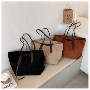 Trois sacs cabas en daim noir, kaki et brun-rouge présentés dans un décor élégant