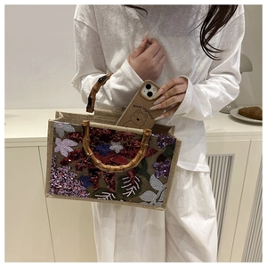 Detailed embroidery of colorful flowers and sequins on a linen tote bag with bamboo handles