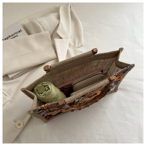 Detail of embroidered tote bag with bamboo handle and sequins in a lifestyle setting