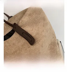 Détail macro du daim kaki et des surpiqûres contrastées sur le sac fourre-tout