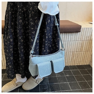 Detail of light blue felt crossbody bag with dual pockets and adjustable strap on a model