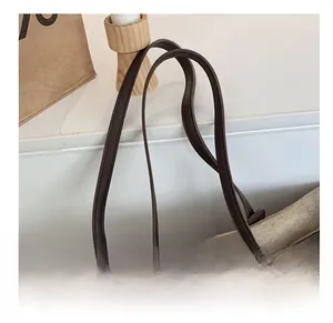 Détail de la bandoulière en cuir marron sur un cabas en daim beige à patchwork