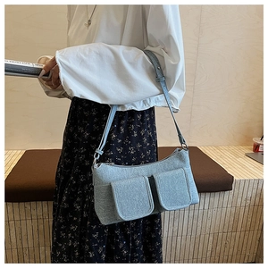 Detail view of light blue textured knit shoulder bag with dual front flap pockets