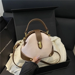Pink crocodile pattern handbag with brown leather trim on silk background