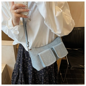 Close-up of light blue crossbody bag with dual front pockets and canvas texture detail