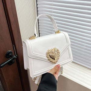 Elegant white patent leather crossbody bag with a large pearl heart buckle and gold chain