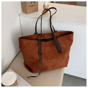Détail d'un sac cabas en daim marron avec une forme trapézoïdale et fines lanières