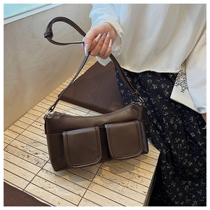Detailed view of dark brown leather underarm bag with double front flap pockets