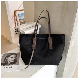 Détail du sac fourre-tout noir mat avec bandoulières marron sur marbre blanc