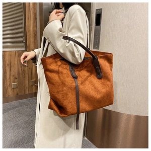 Détail du grand sac cabas en daim caramel avec des anses en cuir marron foncé sur modèle