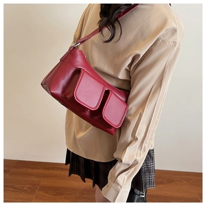Detail of burgundy PU leather baguette bag with two front pockets and adjustable strap