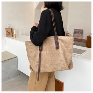 Détail d'un sac cabas en daim camel avec fines bandoulières et design minimaliste