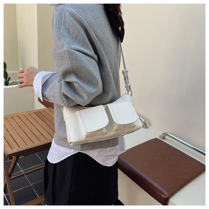 Side view of white PU leather shoulder bag with two front flap pockets worn by a model