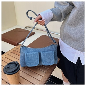 Detail of light blue denim shoulder bag with adjustable strap and front pockets