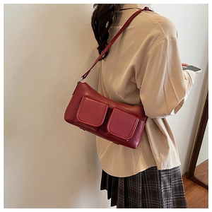 Detail of red faux leather shoulder bag featuring two small front magnetic flap pockets