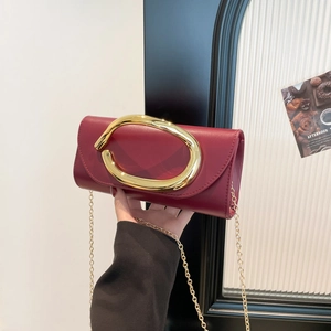 Chic burgundy leather crossbody bag with a large gold oval buckle and metal chain