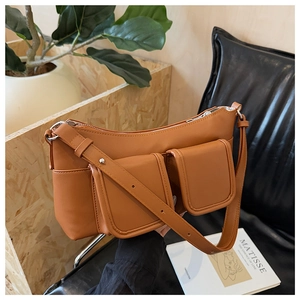 Detail of caramel brown shoulder bag featuring dual functional cargo pockets and silver zipper