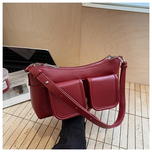 Detail of burgundy underarm bag with double front flap pockets and adjustable strap
