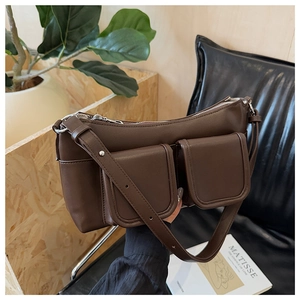 Detail of dark brown leather shoulder bag featuring two front pockets and silver zipper