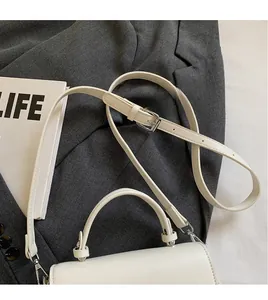 Detail of white leather saddle bag showing adjustable strap and silver metal hardware