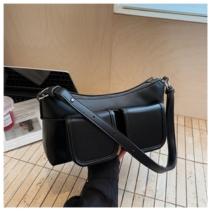 Close-up of black PU leather underarm bag with double front flap pockets and wide strap