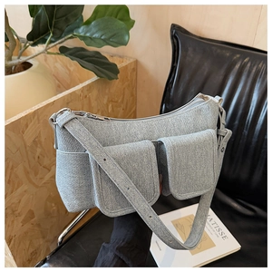 Light blue denim shoulder bag with utility pockets displayed on a black chair