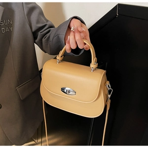 Detail of ginger yellow saddle bag showing the metal twist lock and smooth leather texture