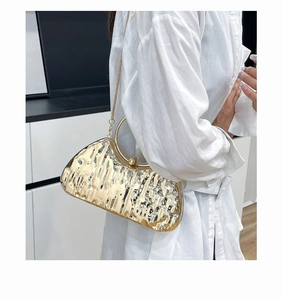 Close-up of golden lava ripple textured evening clutch with metallic round handle