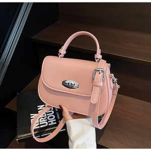 Detail of pink faux leather saddle bag with silver twist lock and adjustable shoulder strap