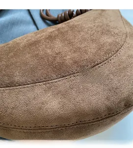 Macro detail of brown suede handbag featuring precision double stitching and knotted handle