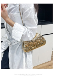 Detail of gold mirror evening clutch with embossed pattern and fine chain strap