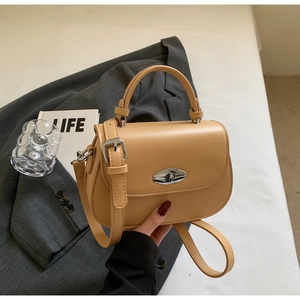 Detail of khaki leather saddle bag showing silver metal twist lock and smooth texture