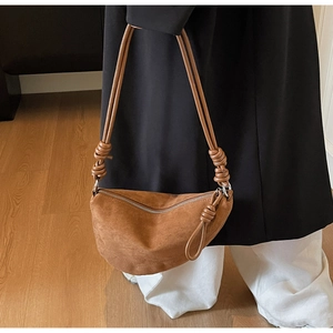 Detail of a brown suede crescent bag featuring a stylish knotted rope shoulder strap design