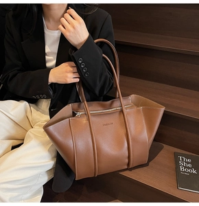 Brown leather tote bag featuring foldable side design and embossed fashion lettering