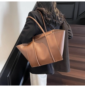 Detail of a large vintage brown leather tote bag with FASHION embossed logo on a shoulder strap
