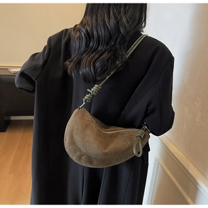 Close-up of suede dumpling bag with unique knot detail on the shoulder strap
